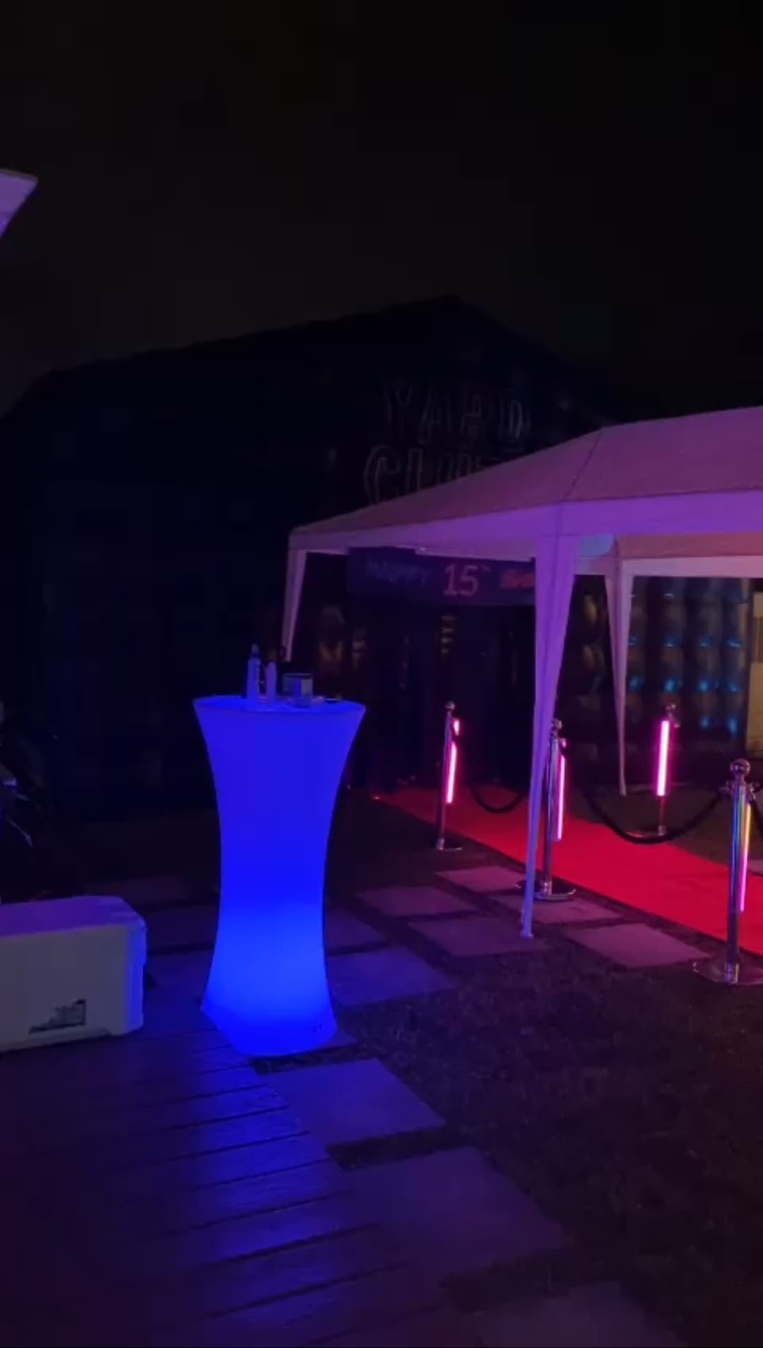 Red carpet, stanchions and a glowing cocktail table outside a Yard Clubs nightclub at night